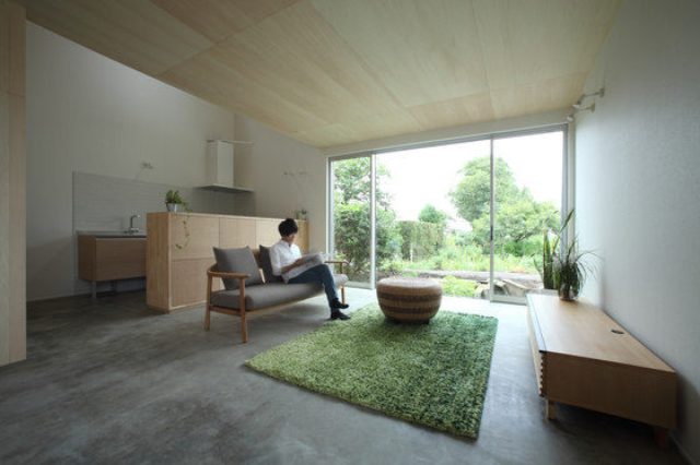 The living room is centered around the glazed wall, and the kitchen is placed in the corner, it's separated with a wood clad kitchen island