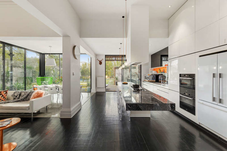 The modern open layout includes a kitchen, a dining space and a living room, there are glazed walls and some orange touches