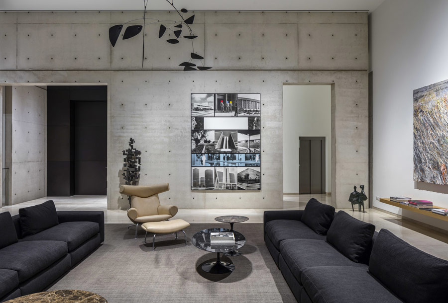 This is the living room that features black sofas, concrete walls and bold artworks including a human figure on the wall