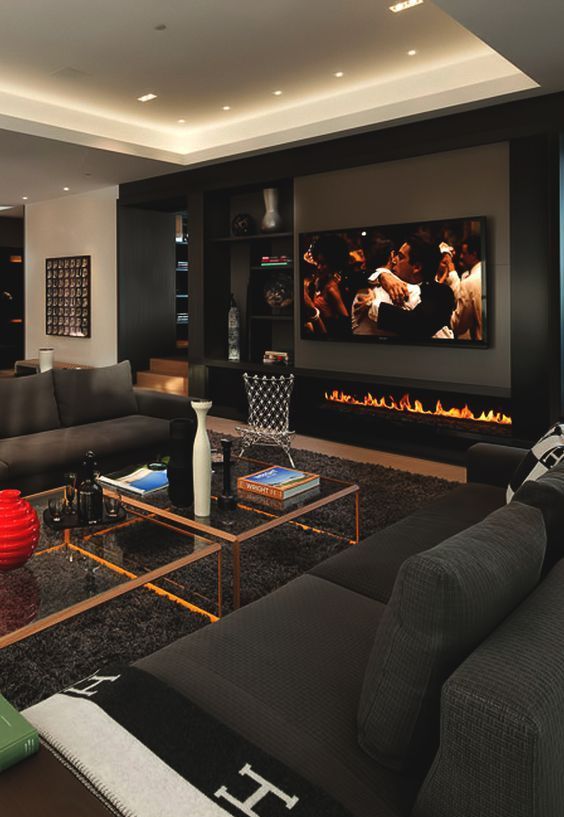a modern man cave with sofas, coffee tables, a fireplace and a large TV to watch sport