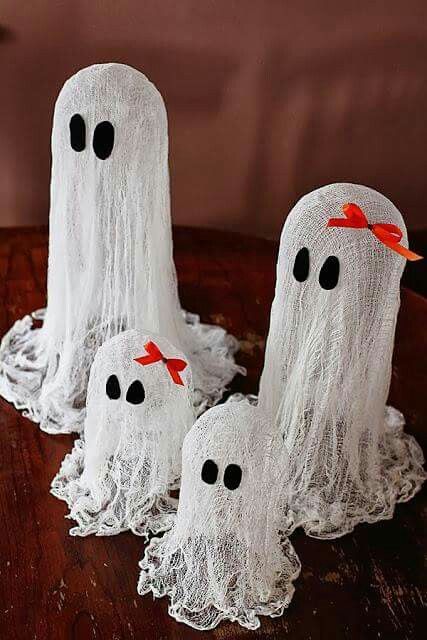small cheesecloth ghosts with black eyes and red bows on top for a table arrangement