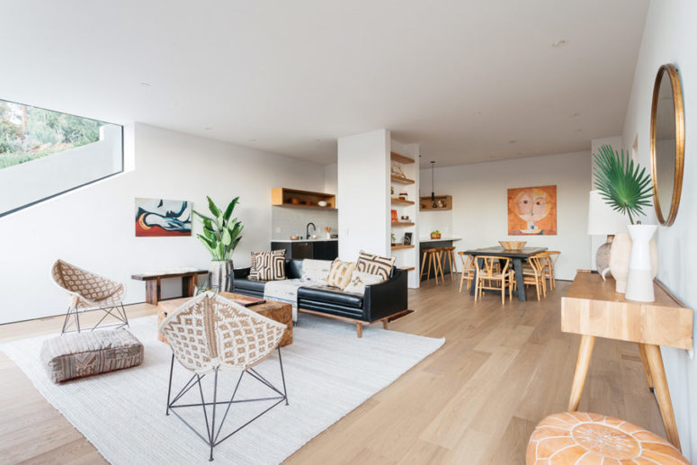 The dining area features a black table and wooden chairs, the artwork repeats the same warm colors