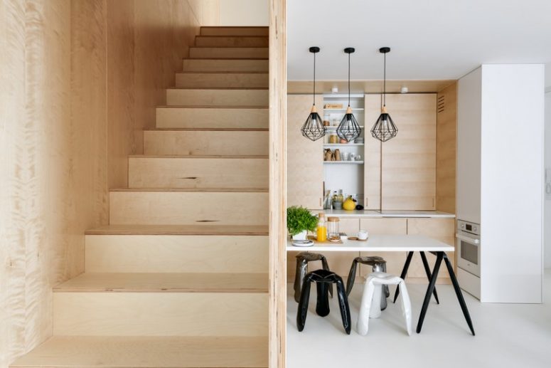 The dining space features a table attached to the wall, modern stools and black pendant lamps