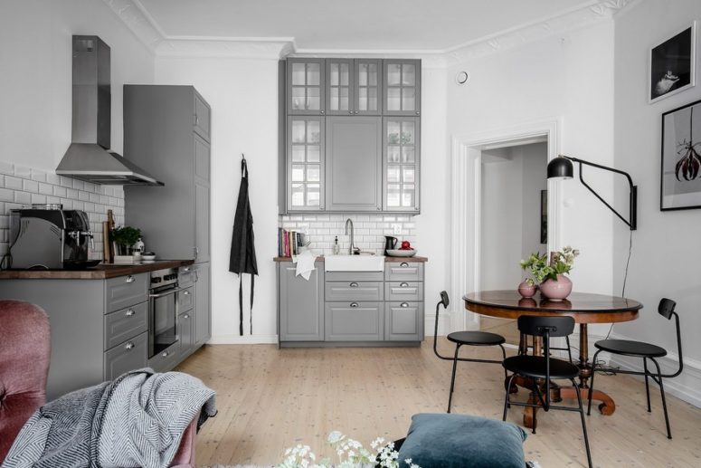 using subway tiles for a backsplash is a great idea The kitchen is grey, with white subway tiles backsplashes and there's a small dining space with black chairs and a wooden table