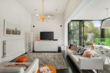 03 The living space features neutral furniture and decor and some bold orange touches
