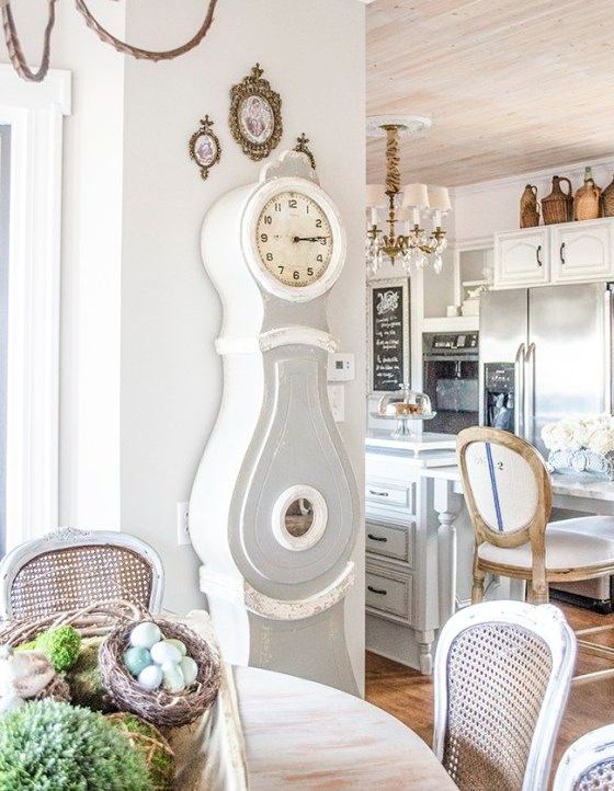 a shabby farmhouse kitchen and dining space with a grandfather's clock in grey and white