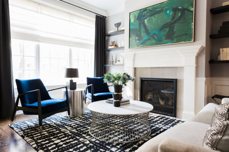 A fireplace, open shelving and lots of light make this living room ethereal, while a green artwork and cobalt blue chairs add color A fireplace, open shelving and lots of light make this living room ethereal, while a green artwork and cobalt blue chairs add color