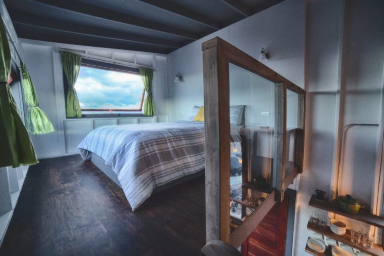 The bedroom features two windows to enjoy the views and a wooden railing with glass to make it separated yet not to cut the space
