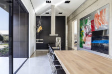 04 The kitchen is black and sleek, there’s a big kitchen island, bold artworks and a breakfast zone