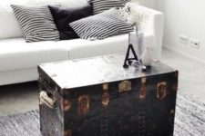 04 a Scandinavian room in black and white is ade more eye-catchy with a black vintage trunk, which serves as a coffee table