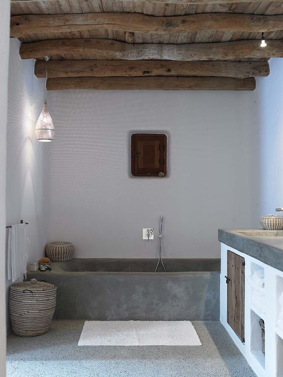 a modern Mediterranean bathroom look is achieved with rough concrete, wood and wicker baskets