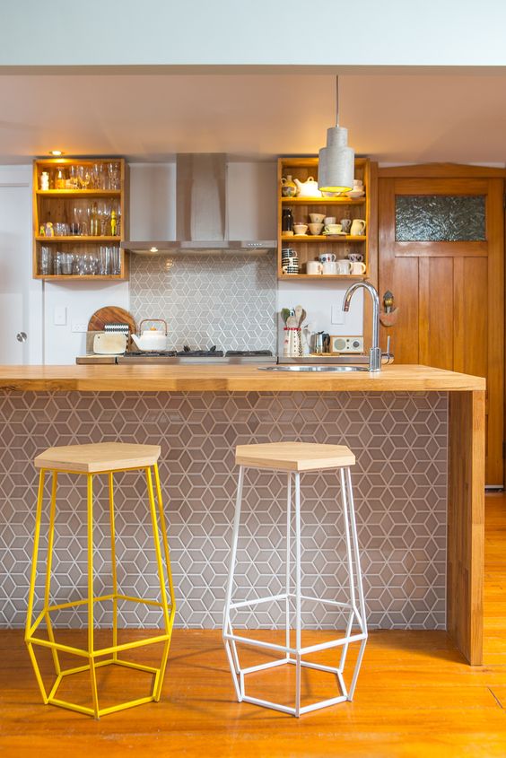 a stylish bar counter clad with geo tiles that echo with the backsplash and wood with geometric stools