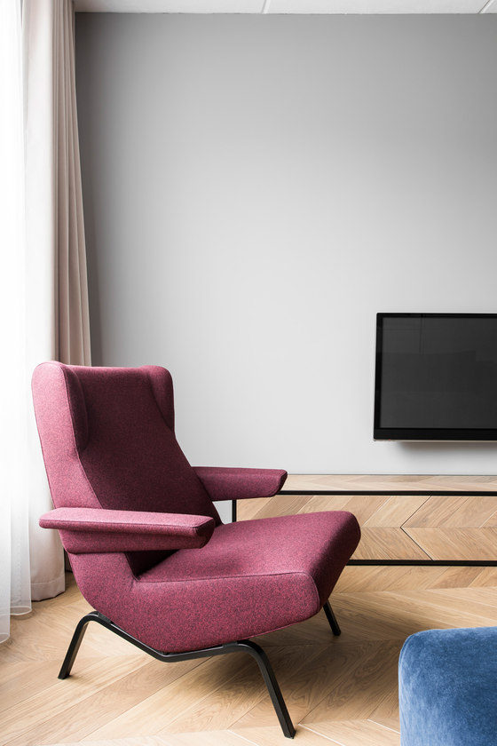 A geometric shaped maroon armchair adds color to the neutral and muted space