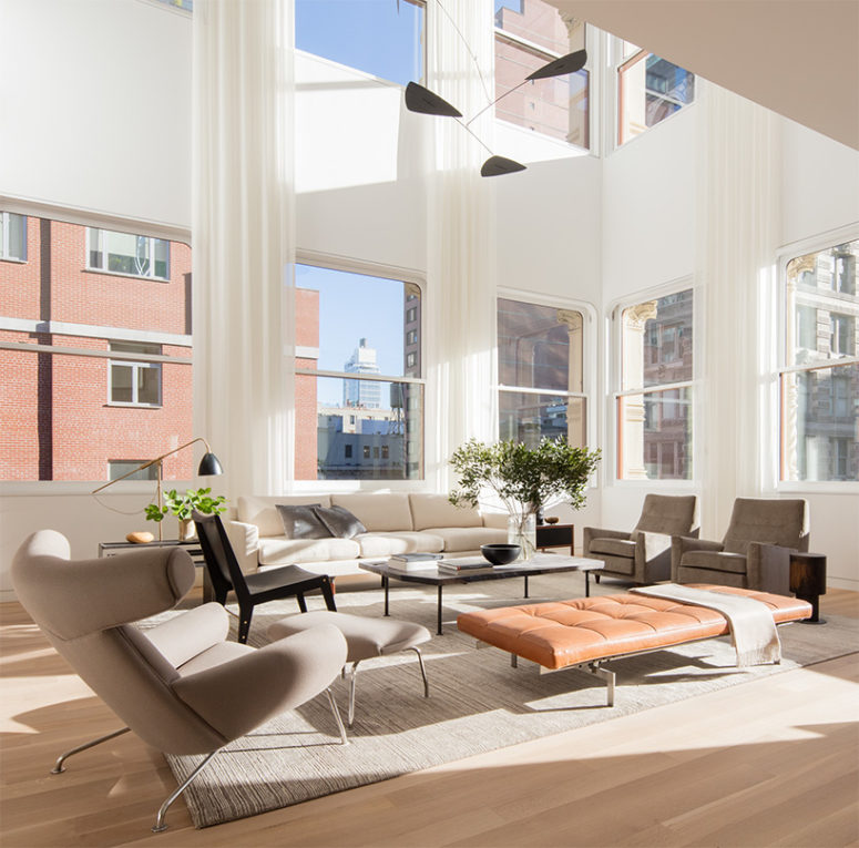An amber leather couch makes a slight stylish accent in this neutral double-height space