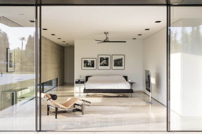 The master bedroom is in a separate volume, there's a black bed, mismatching nightstands and a modern lounger The master bedroom is in a separate volume, there's a black bed, mismatching nightstands and a modern lounger