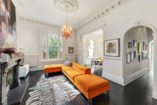 05 This room features bold orange furniture and an antique fireplace, a bold artpiece catches an eye
