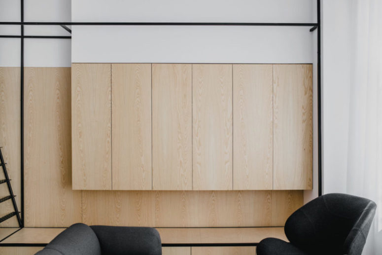 Wooden cabinets and a black frame staircase that leads upstairs to the bedroom