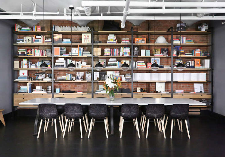 storage in a dining room The dining space features large bookshelves that cover the whole wall, a long marble table and black chairs