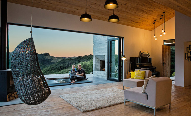 The living room is cozy and simple, with a hearth, a hanging chair, some comfy modern furniture and rugs