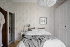 06 The master bedroom features neutral floral print wallpaper, a large comfy bed, wardrobes and wooden floors to create a cozy ambience