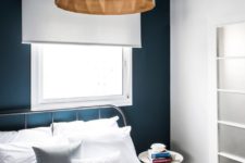 06 There’s a large bed, a geo shaped wood lamp and a navy accent wall