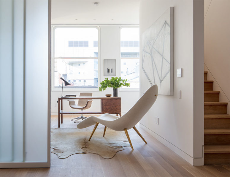 The home office features a stylish small desk, artworks and a unique geometric chair on brass legs