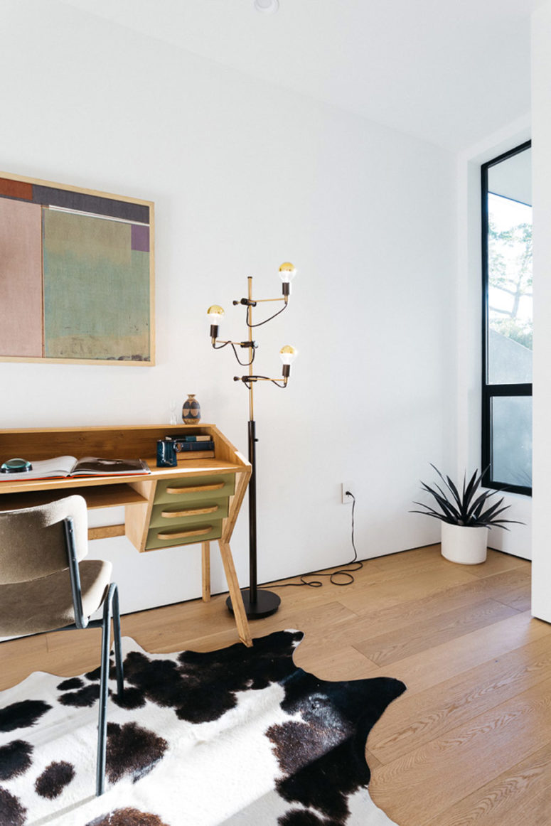 The home office is cozy and small, just a wooden desk with drawers and a comfy chair, an animal print rug adds coziness