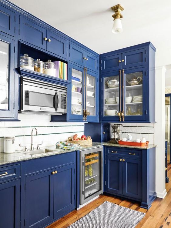 a bold blue kitchen with neutral countertops and brass handles for a vintage feel