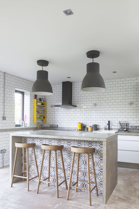 a concrete countertop is durable and accentuated with colorful mosaic tiles and stylish wooden stools