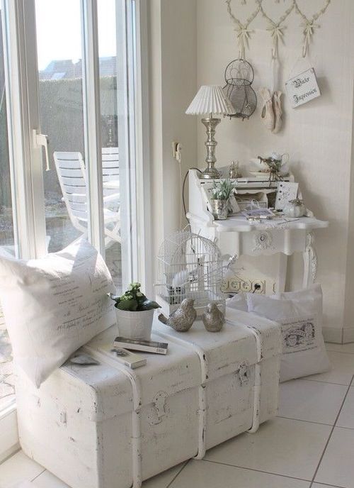 a vintage chest painted white to match shabby chic decor is used as a side table
