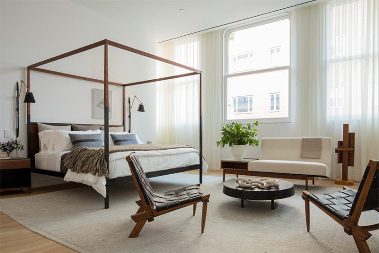 The master bedroom shows off black leather belt chairs, a black and brown bed with framing, and a cozy love seat with a storage space