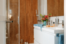 08 The mom’s bathroom looks luxurious and modern, with a wood clad wall in the shower