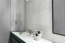 09 The bathroom was decorated with white tiles of different textures, a green vanity and a mirror