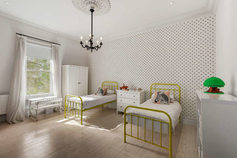 A shared kids' bedroom has vintage beds painted yellow, a study space by the window and a wardrobe
