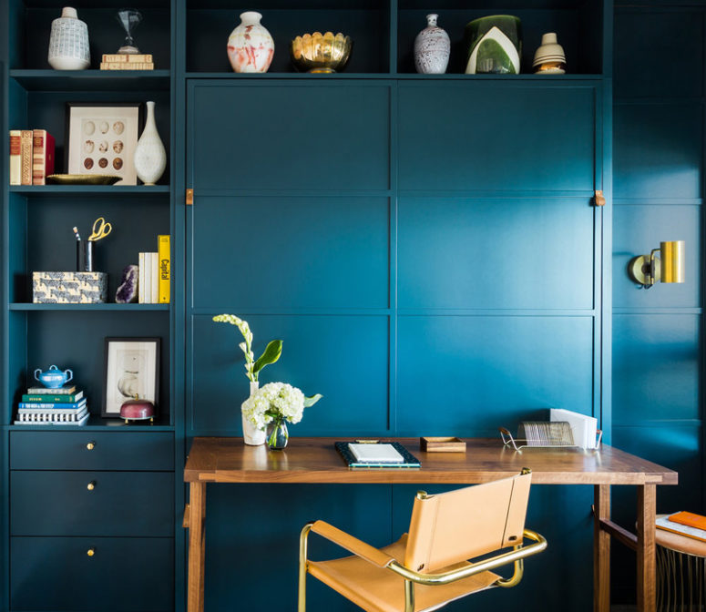 The home office is navy, with a large shelving unit, a small desk and chair