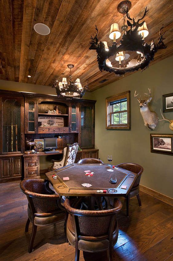 a rustic man cave with taxidermy, leather chairs, antlers and wooden furniture