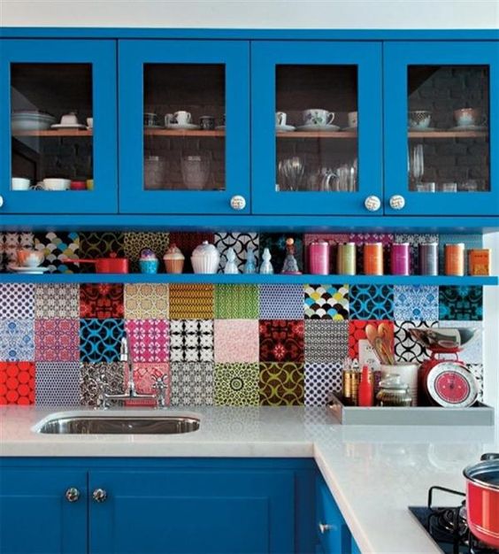 bright-colored blue kitchen with sleek white countertops and a bold assorted tile backsplash
