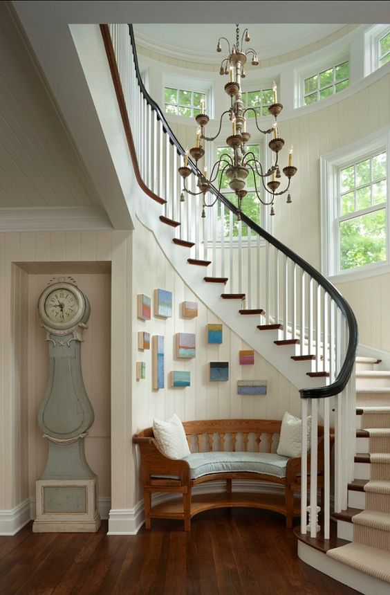 a coastal entryway with a dusty blue grandfather's clock and a rounded bench