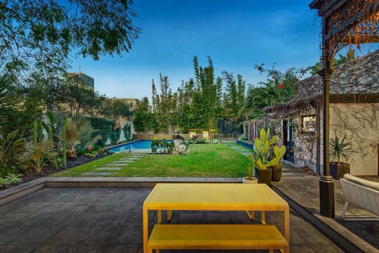The outdoor space features bold yellow furniture, living walls and a swimming pool