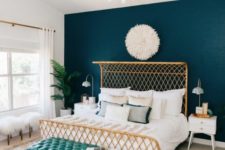 a glam art deco bedroom with a teal statement headboard wall and brass accents