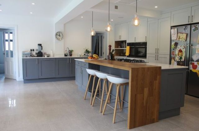 the kitchen island with a bar countertop has two parts - a cooking zone for the kitchen and a wooden countertop for eating