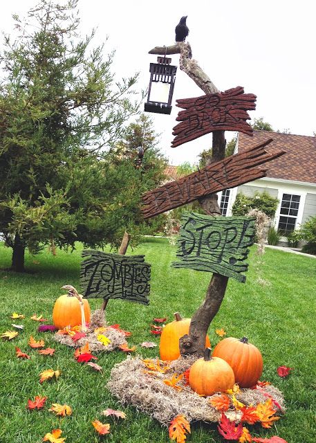 a large branch with colorful signs, faux fall leaves and pumpkins, a faux raven and a lantern