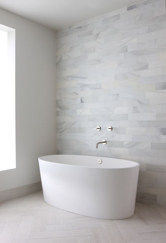 marble tile statement wall and matte neutral tiles on the floor create a relaxing and inviting space