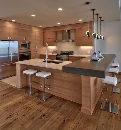 a kitchen island with a concrete countertop on the side accentuated with pendant lamps