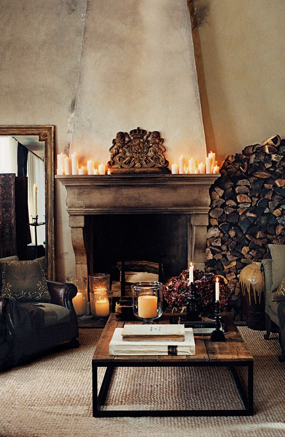 an antique rustic fireplace with firewood inside and candles on the mantel