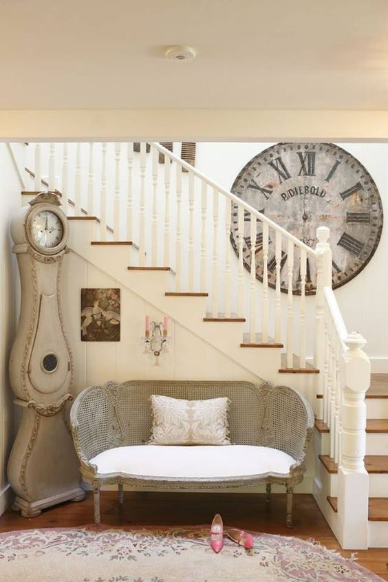 a French farmhouse hallway with a vintage clock and a cute loveseat