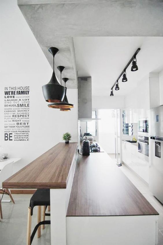 a large two-level kitchen bar counter includes an eating space and a kitchen island and is accentuated with pendant lamps