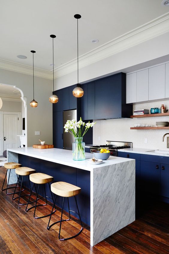 a dark blue modern sleek kitchen with white marble and white cabinets