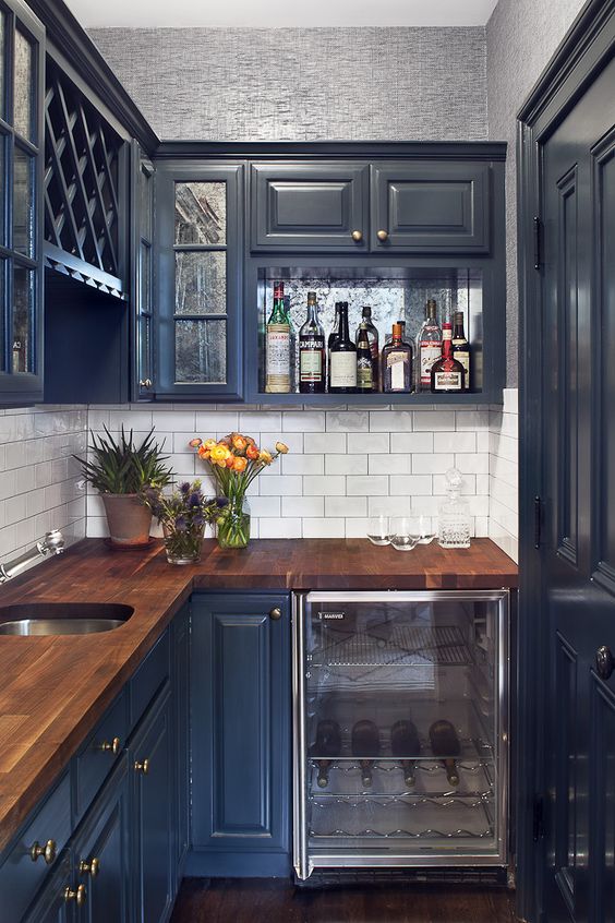 a small dark blue kitchen with a saturated wooden countertop looks chic