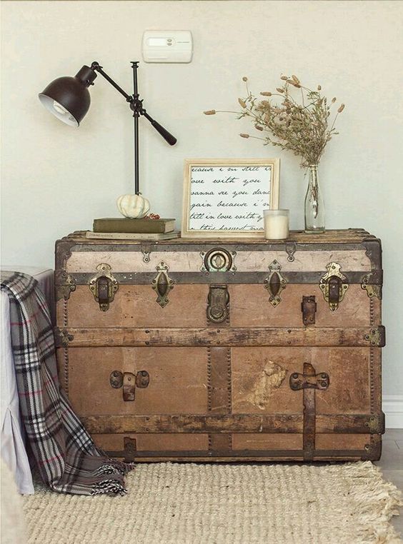 a wooden trunk with brass detailing is used as a console table for a living room